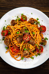 Spaghetti with meatballs in tomato sauce on wooden table
