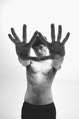 Inner world. Black and white photography of young handsome asian guy standing with outstretched arms. Male model posing shirtless. Concept of male body aesthetics, style, fashion, health, men's beauty