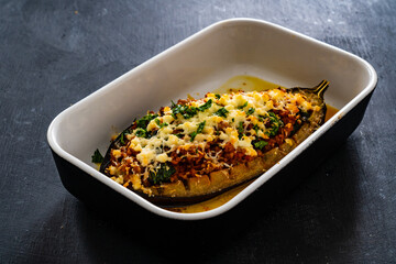 Roasted aubergine stuffed with minced meat and cheese on wooden table
