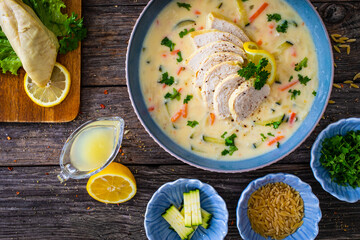 Greek lemon creamy soup with cooked chicken breast on wooden table

