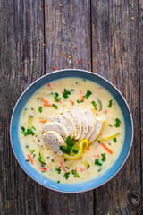 Greek lemon creamy soup with cooked chicken breast on wooden table

