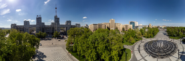 Aerial view on Derzhprom and northern Karazin National University buildings on Freedom Square with circle fountain, spring greenery and blue sky in Kharkiv, Ukraine