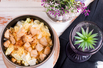 vegetable salad with fried chicken breast in a deep dish. Serving on a wooden background with a black napkin and cutlery