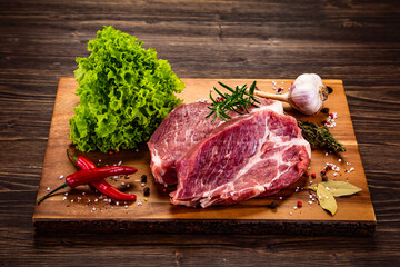 Fresh raw slices of pork neck on cutting board on wooden table

