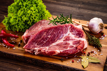 Fresh raw slices of pork neck on cutting board on wooden table


