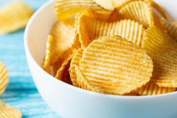 Close-up, a plate of potato chips on a blurred background.