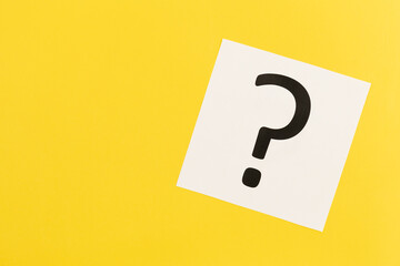 Question mark on white paper on yellow background, flat lay.
