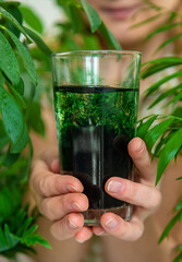 A woman drinks liquid chlorophyll. Selective focus.