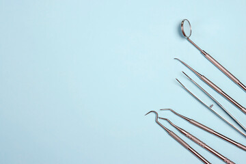 Dentist tools on blue background with copy space.  Professional steel dental instruments with a...