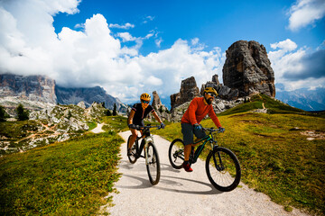 A man and woman ride electric mountain bikes in the Dolomites in Italy. Mountain biking adventure...