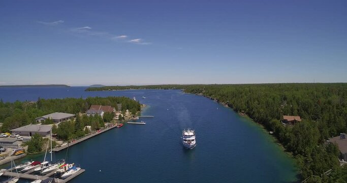 Aerial footage of a boat riding on water on the harbor in Tobermory, Ontario, Canada