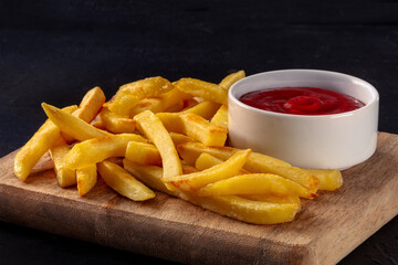 French fries, potato snack with ketchup, fast food on a black slate background, with copy space