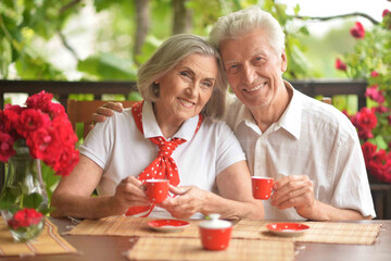 old couple is sitting at a table and drinking tea