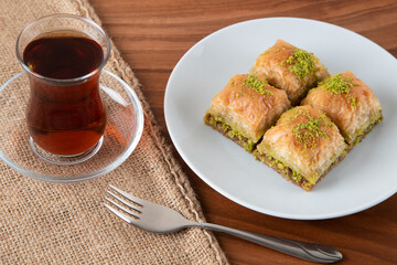 Traditional pistachio baklava with Turkish tea.A plate of baklava on wooden table
