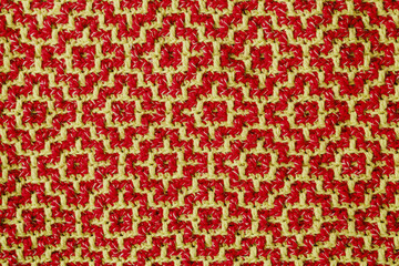 Knitted texture with yellow red geometric ethnic pattern. Crochet mosaic pattern. Rhombus and square pattern.