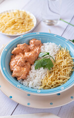 Close-up of Chicken strogonoff with rice and potato straw on white wooden table. Brazilian cuisine.
