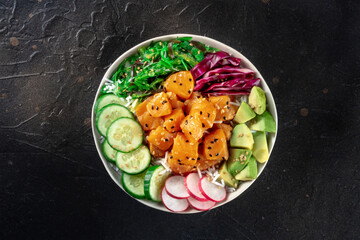 Salmon poke bowl with avocado, cucumbers, wakame, radish, and purple cabbage, a healthy Hawaiian...