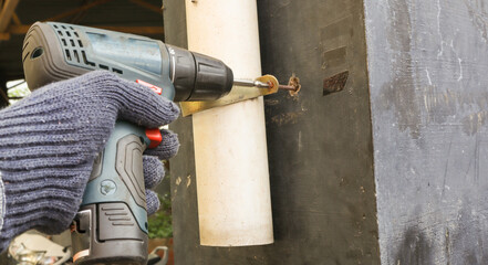 A Home repair work in progress where a rusted screw is being removed by an electric driver by a carpenter in India.