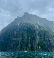 Mesmerizing landscape of forested cliffs in the clouds captured from the sea in New Zealand