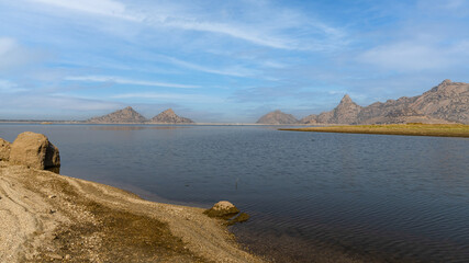 View of pristine landscape of Jawai Dam with hills and clouds in the background 