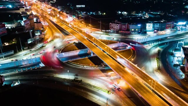Hyperlapse time-lapse of car traffic transportation above circle roundabout road in urban downtown Asian city at night. Drone aerial view, high angle. Public transport or commuter city life concept