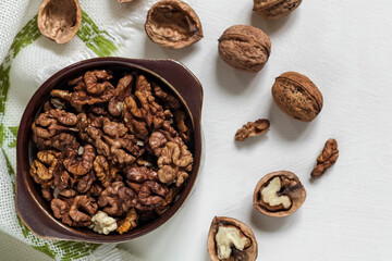 Bowl with organic peeled walnuts and whole walnuts on a white background. Copy space.