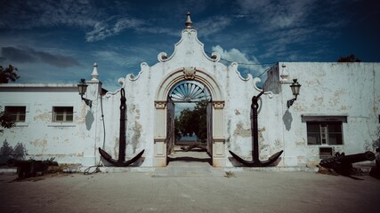 Entrance of a building decorated with big anchors on Mozambique island against the blue sky © Bruno Pedro/Wirestock Creators