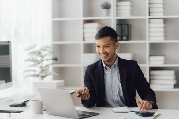 Fototapeta premium Happy working asian businessman talking on the phone with accounting documents at desk in happy working office