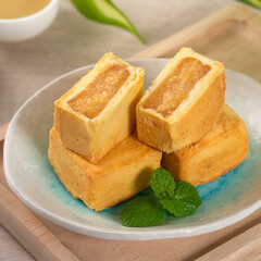 Delicious pineapple cake pastry in a plate on wooden table background with tea.