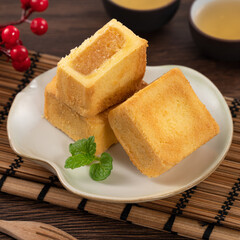 Delicious pineapple cake pastry in a plate on wooden table background with tea.
