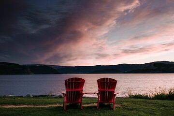 Scenic view of two red benches on the shore of a tranquil lake against hills at pink sunset