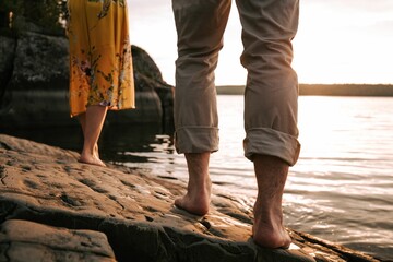 Closeup of a man's and woman's feet on a rocky shore on a lake at golden hour