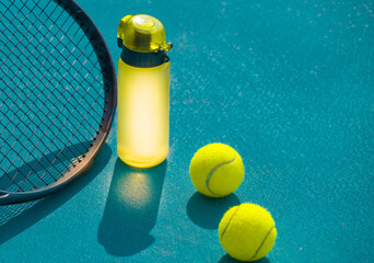 Tennis racket, ball and water bottle on hard blue court