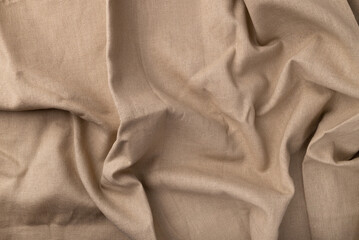 Natural linen fabric texture. Flaxen textile background, top view. Rough crumpled burlap