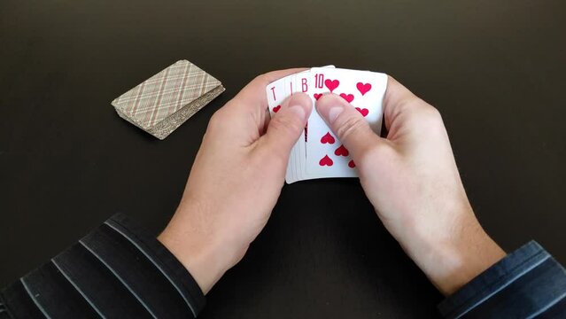 Playing cards in the hands on a black table background
