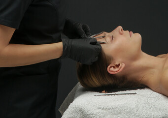 Fototapeta premium Mikrobleiding eyebrow measurement. Cosmetologist makes markings with pencil and threads for perfect shaped eyebrows. Professional makeup and facial care. Permanent makeup, tattooing of eyebrows. 