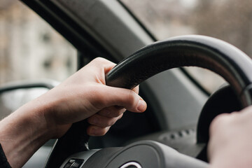 Drivers's hands on a stearing wheel of a car