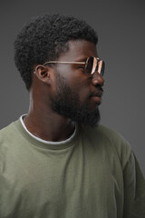 Portrait of trendy black man with beard and sunglasses isolated on grey background.