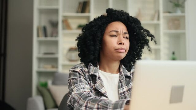 Sad african american woman student or freelancer with lack of new ideas or creative block typing and deleting text on laptop computer at home Worried female changing her mind every few seconds indoors