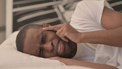 Fototapeta na wymiar Side View of African Man with Headache Lying in Bed 