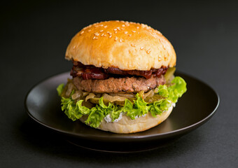 Close-up of a delicious fresh homemade burger with lettuce, onion and tomato on a dark background