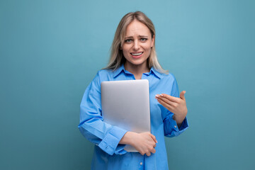 cute blond girl student holding a laptop in her hands on a bright blue background