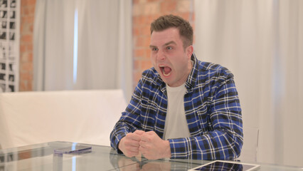 Angry Young Casual Man in Frustration Sitting in Office