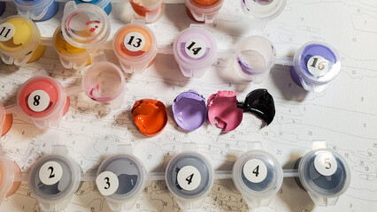 Painting on canvas by numbers with acrylic paints. The paint for drawing has dried up