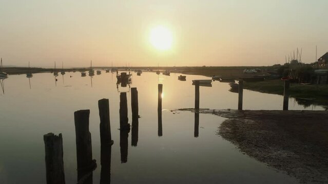 Low Establishing Aerial Drone Shot Flying Over Burnham Overy Staithe Harbour and Small Boats into the Sun at Sunrise on Misty Morning North Norfolk UK East Coast