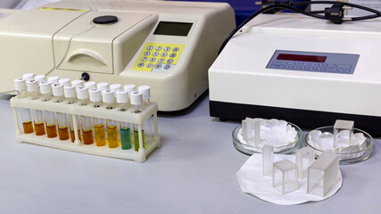 laboratory table with multi-colored reagent vials in the stand, clean plastic cuvettes and measurement machines