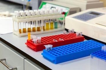 laboratory table with multi-colored reagent vials in the stand, disposable plastic test tubes and measurement machines
