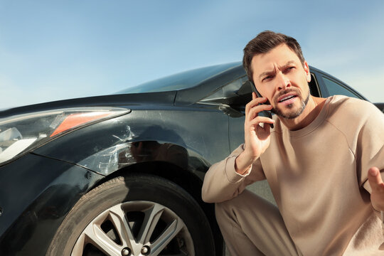 Man Talking On Phone Near Car With Scratch Outdoors