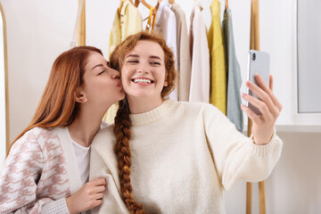 Beautiful young sisters taking selfie in dressing room