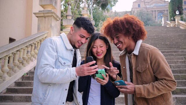 Group of multiracial teenagers watching funny videos on a social media app using a cellphone. Three young friends sharing content and having fun together with a smartphone.. happy people with phone